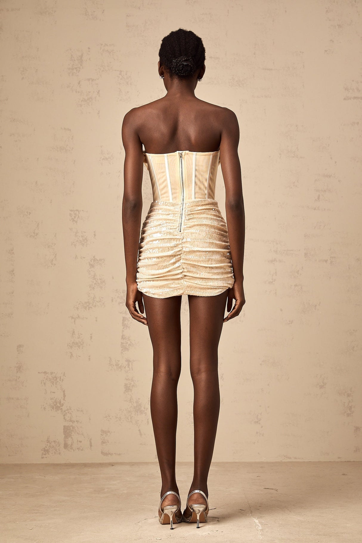 A short beige tulle mini dress with allover sequin embellishment and a sleeveless design featuring a fitted silhouette and scoop neckline