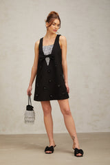 A short black dress with 3d floral sequin details covering the fabric creating a textured petal pattern The dress has a fitted silhouette and falls to mini length