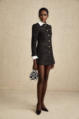 A short black dress with a tweed body and sequin panels featuring a mini length and sleeveless design inspired by Audrey Hepburn style