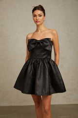 A short black metallic mini dress with a bow detail and a shiny finish