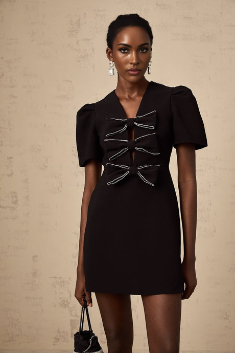 A short black mini dress with a decorative bowknot detail