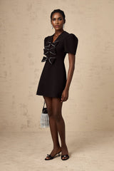 A short black mini dress with a decorative bowknot embellishment