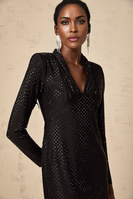 A short black mini dress with a plunging V neckline adorned with studded embellishments and featuring long sleeves