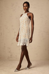 A short black mini dress with sparkling embellishments and fringe detailing along the hem and sleeves