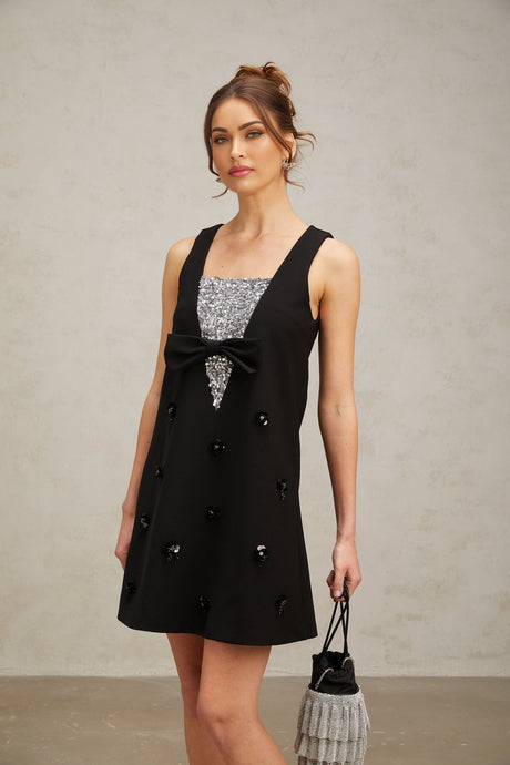 A short black mini dress with threedimensional petal shaped sequins covering the fabric creating a textured and shimmering effect