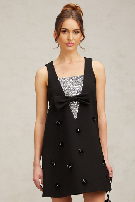 A short black mini dress with threedimensional petalshaped sequins covering the fabric creating a textured and shimmering effect