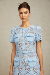 A short blue dress with floral lace appliques and ruffled details featuring a mini length and delicate floral pattern throughout