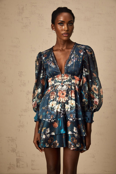 A short blue mini dress with a graphic print pattern and embellishments worn by a model named Candice
