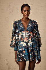 A short blue mini dress with a graphic print pattern and embellishments worn by a model named Candice