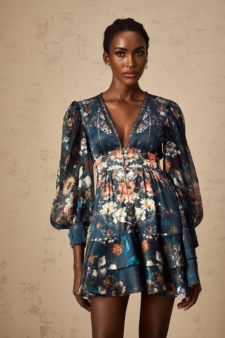 A short blue mini dress with a graphic print pattern and embellishments worn by a model named Candice