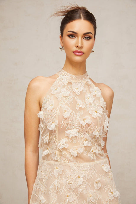 A short cream colored lace mini dress with delicate floral appliques scattered across the fabric featuring a feminine silhouette and neutral tones