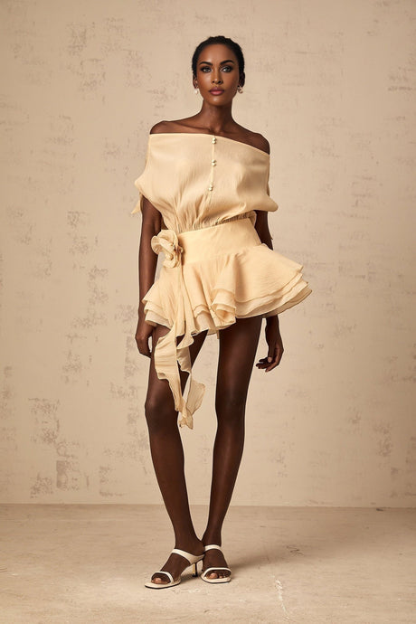 A short floral dress with ruffle details and floral applique decorations on a light colored fabric