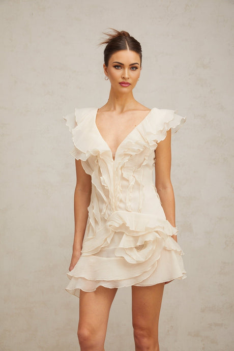 A short floral patterned mini dress with multiple ruffled layers and a faux flower embellishment