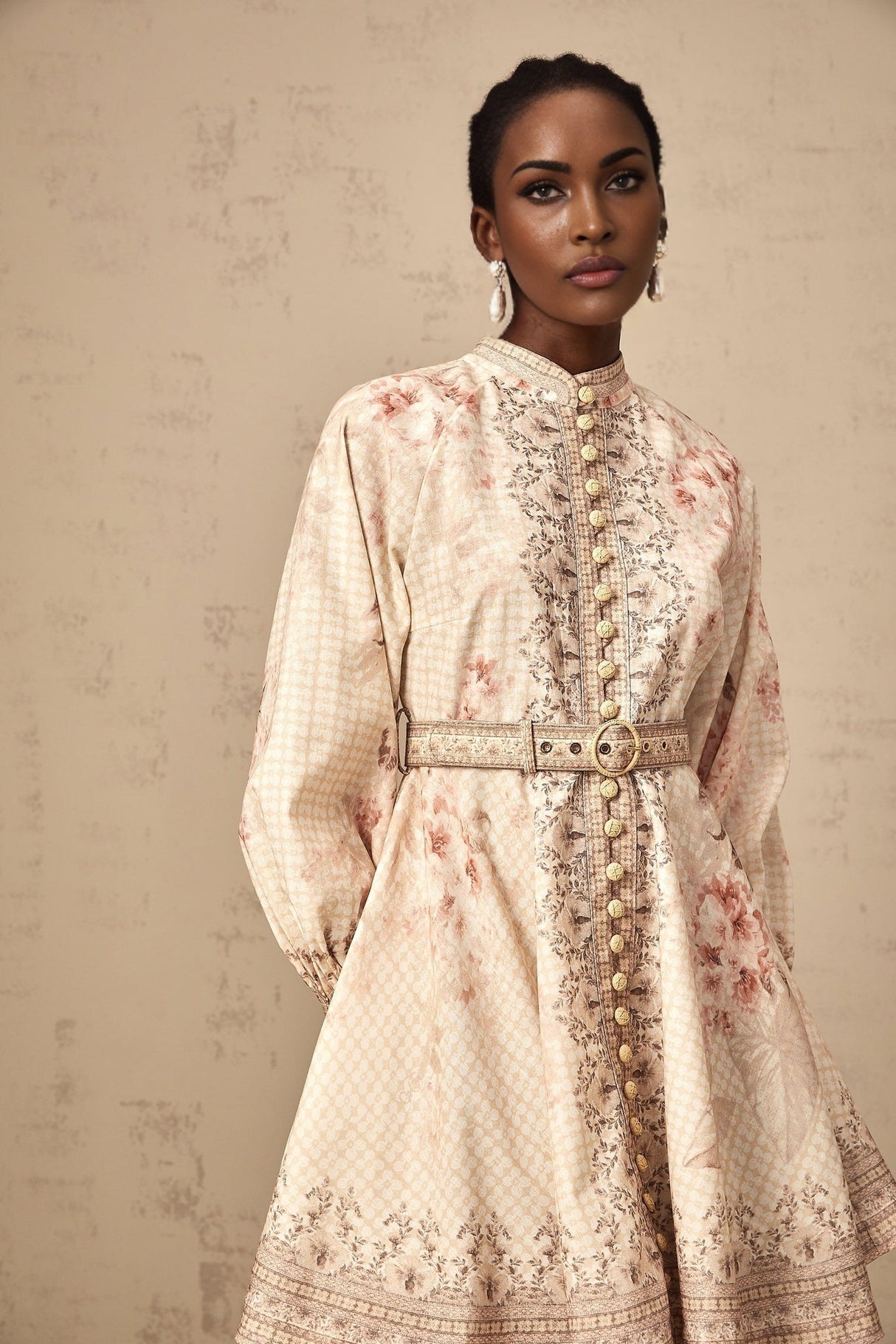 A short floral print mini dress with a belt accent cinched at the waist featuring a vibrant pattern and feminine silhouette