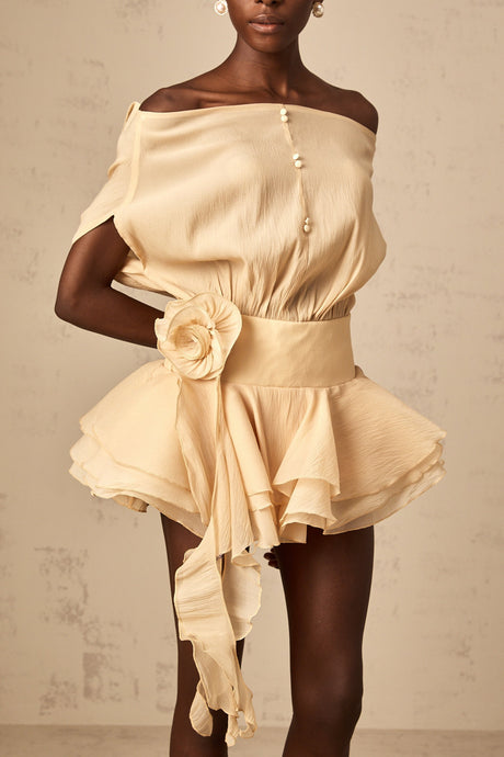 A short flounced mini dress with colorful floral applique decorations on a light background