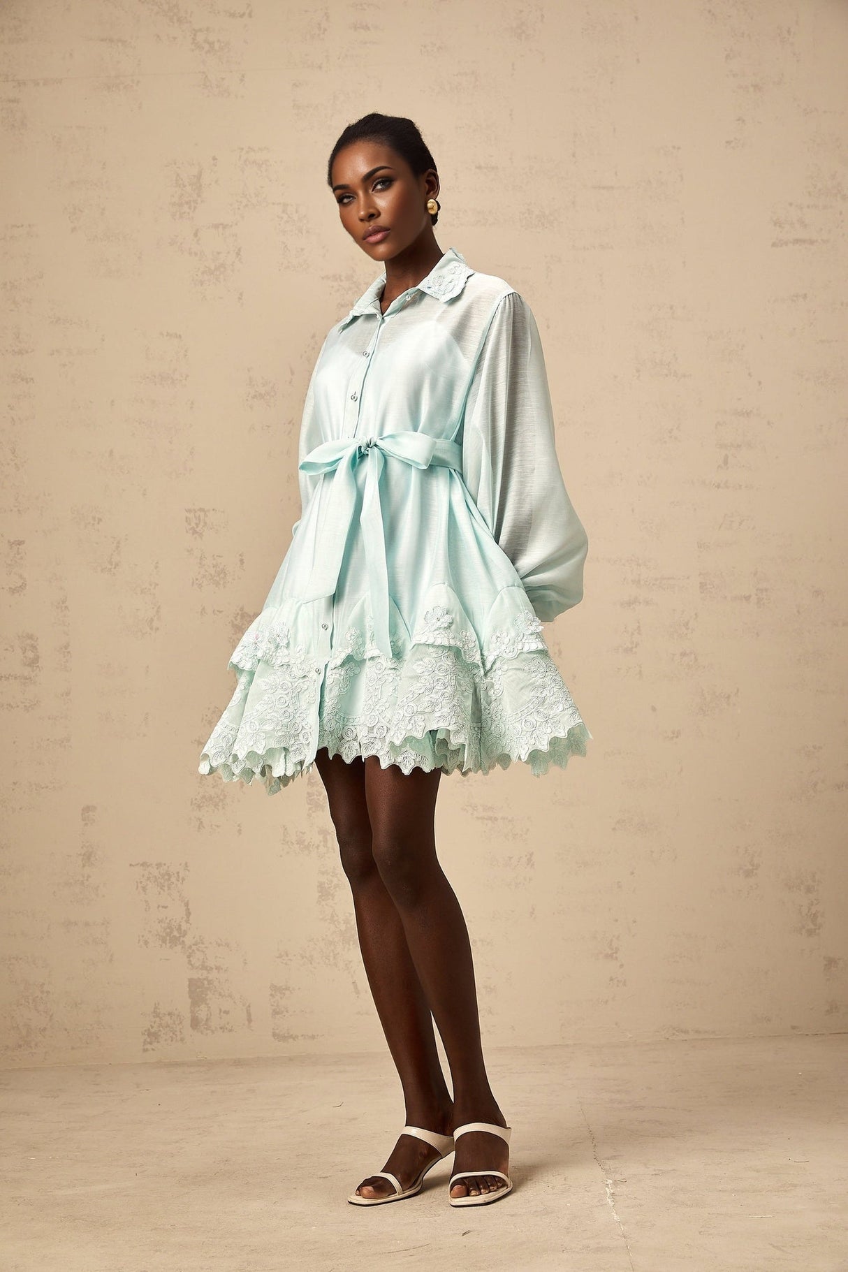 A short green dress with lace panels and a shirtstyle design featuring a collar and buttons