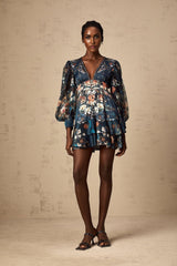 A short light blue mini dress with a graphic print pattern and embellishments worn by a model standing against a plain background