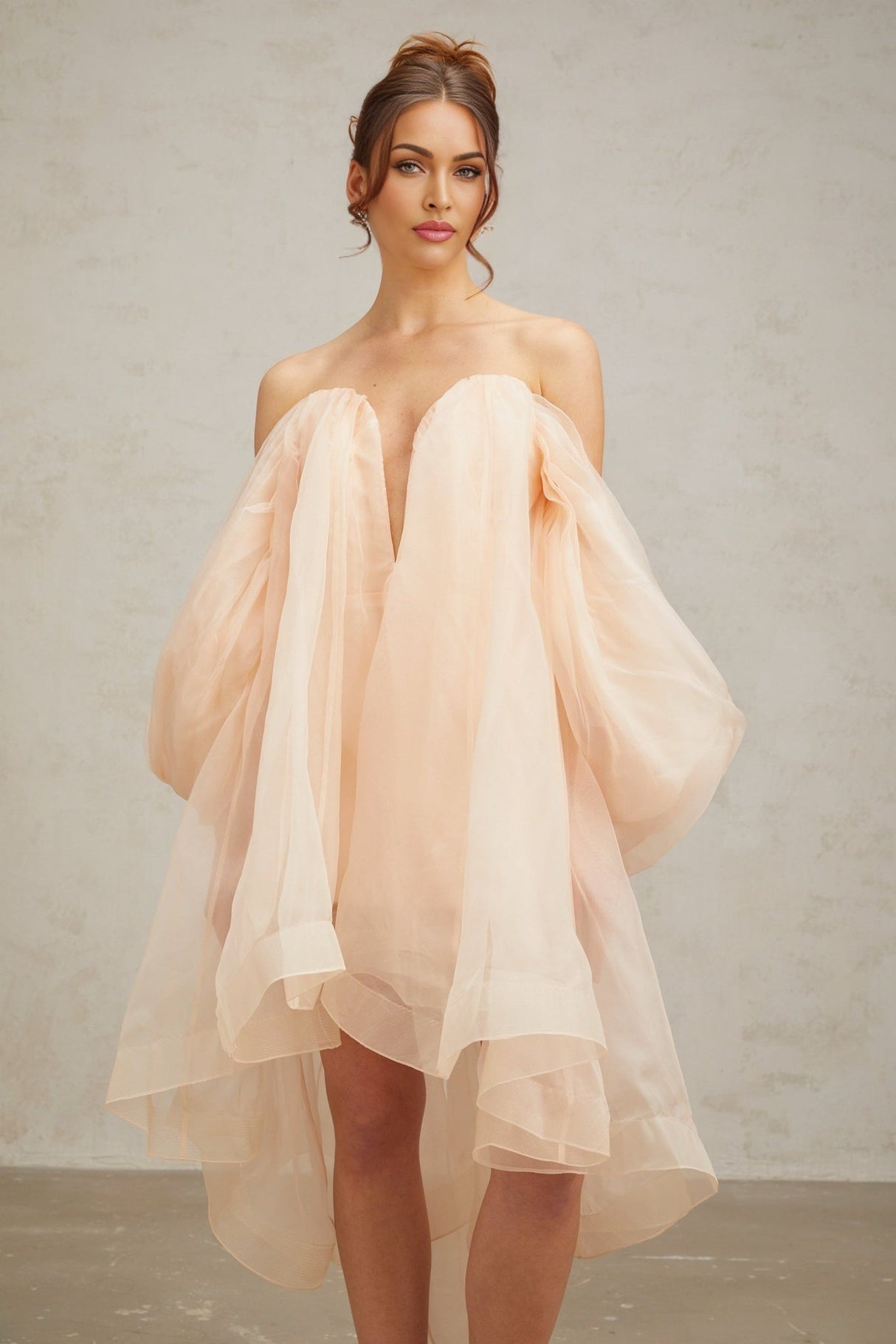 A short light colored dress with voluminous sleeves and skirt featuring a prominent bow detail