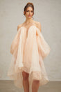 A short light colored dress with voluminous sleeves and skirt featuring a prominent bow detail