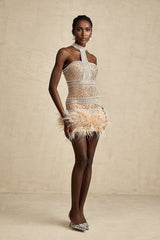 A short light colored mini dress with crystal embellishments and feather trim along the hem and neckline