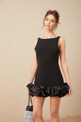 A short light colored mini dress with ruffled details and an open back design