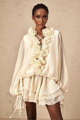 A short light colored tiered mini dress with floral applique details called Zephyrine