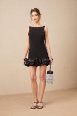 A short lightcolored mini dress with ruffled details and an open back design