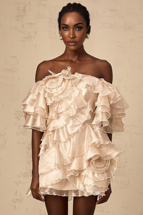 A short neutral colored dress with an asymmetric design featuring a flounce detail and a mini length