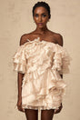A short neutral colored dress with an asymmetric design featuring a flounce detail and a mini length