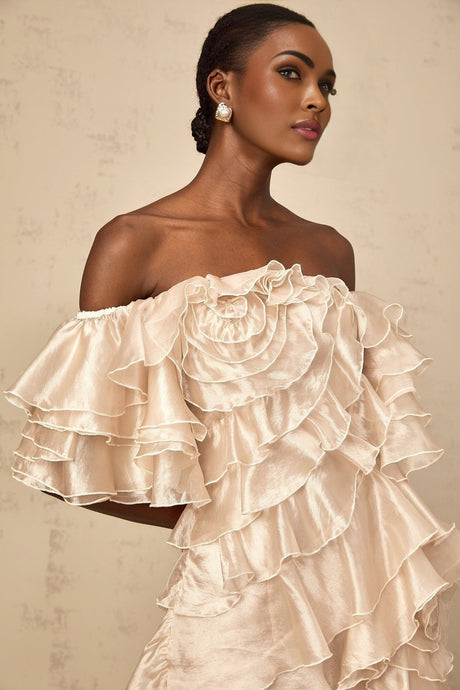 A short neutral colored mini dress with an asymmetric design featuring a flounce detail and a cerise pink accent