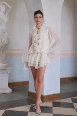 A short neutral colored mini dress with multiple tiers and floral applique details called Zephyrine