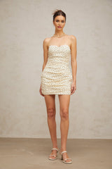 A short neutral colored mini dress with polka dot pattern and ruched detailing