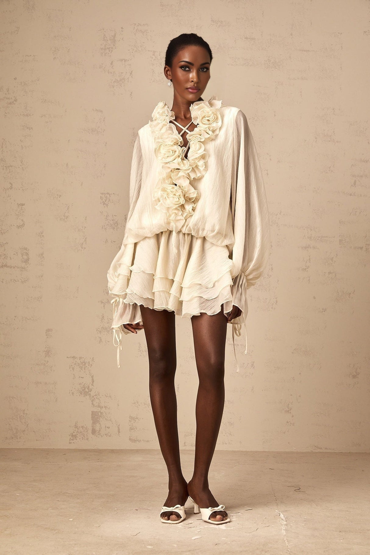 A short neutral colored tiered mini dress with floral applique details on the bodice and skirt named Zephyrine