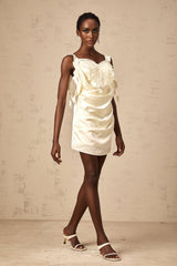 A short neutralcolored mini dress with a butterflyinspired draped design featuring the name Sylvia