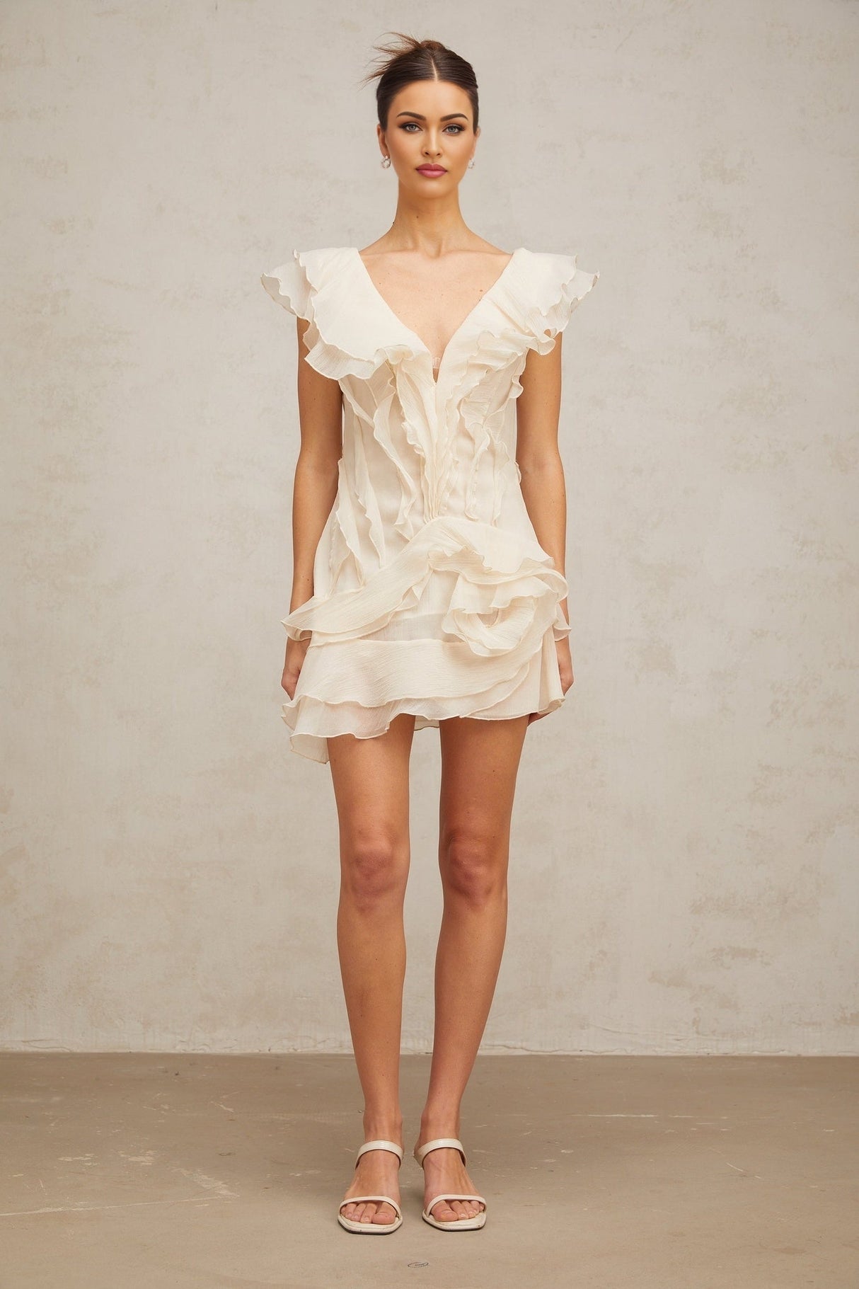 A short pink dress with multiple layered ruffles and floral embellishments inspired by faux flowers