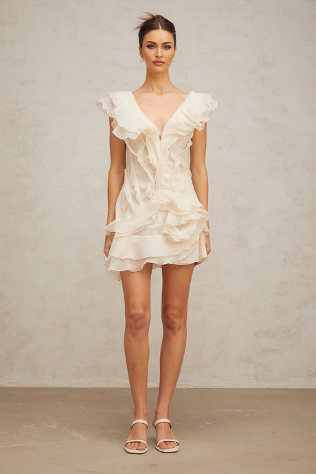 A short pink dress with multiple layered ruffles and floral embellishments inspired by faux flowers