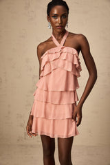 A short pink halter dress with tiered ruffles and a mini length skirt