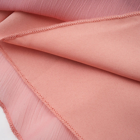 A short pink halterneck dress with tiered layers and a mini length skirt