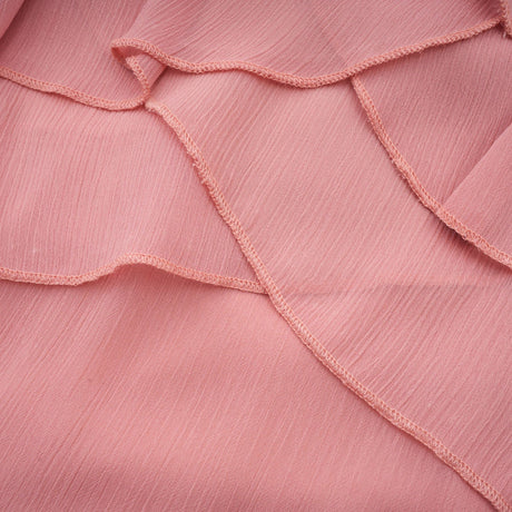 A short pink halterneck dress with tiered ruffles and a mini length skirt