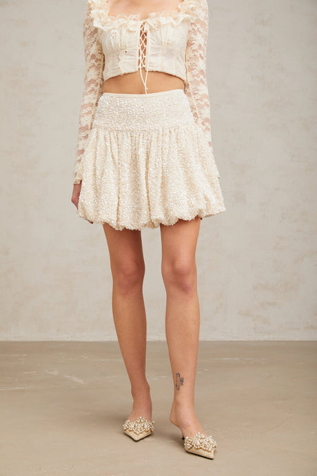 A short pleated mini skirt with shimmering sequins covering the fabric likely in a festive or glamorous style