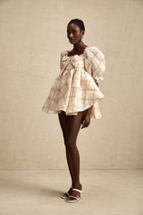 A short puffy mini dress with a checkered pattern featuring a prominent bow detail at the neckline