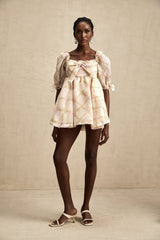 A short puffy mini dress with a checkered pattern featuring a prominent bow detail