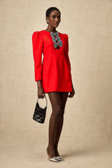 A short red mini dress with a split skirt featuring a studded bow detail and a fitted silhouette