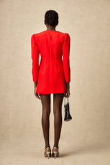 A short red mini dress with a split skirt featuring a studded bow detail at the waist