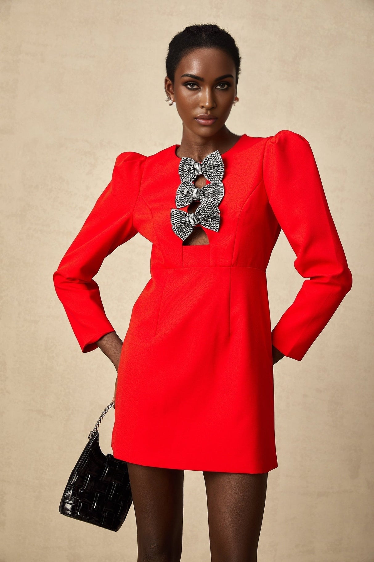 A short red mini dress with a split skirt featuring decorative studs and a bow detail
