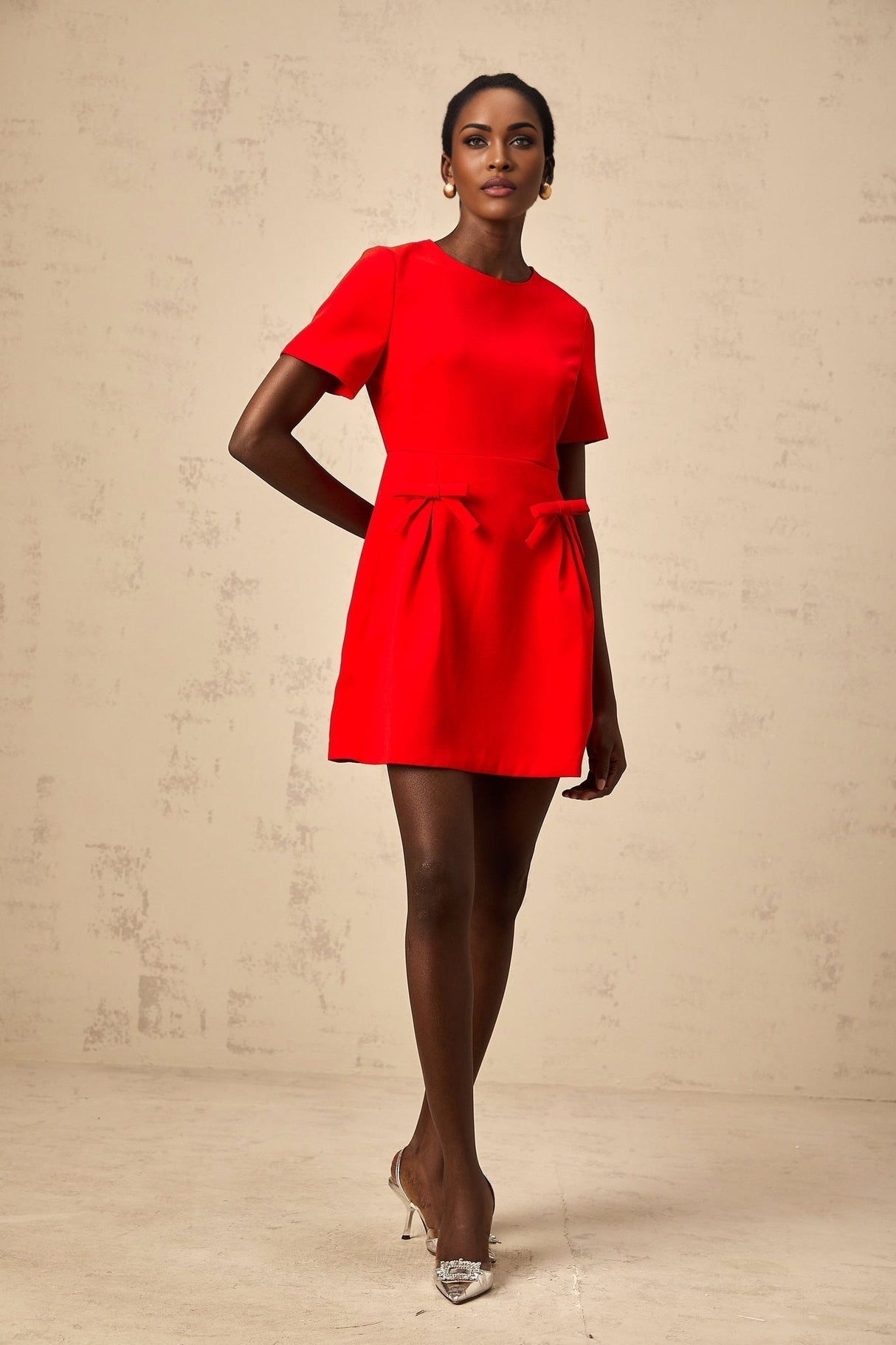 A short red mini dress with short sleeves and a bow detail featuring a feminine and playful design