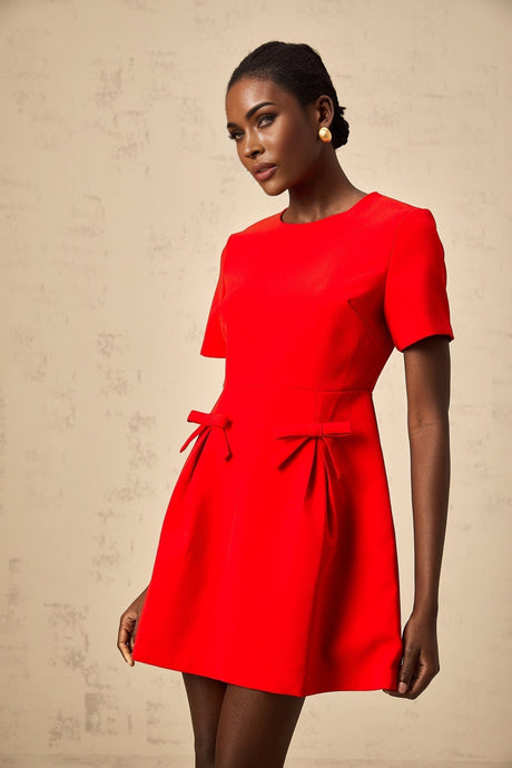 A short red mini dress with short sleeves and a bow detail visible on the front