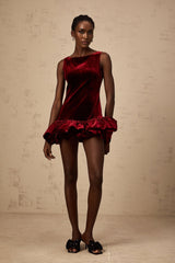 A short red velvet dress with a peplum hem and mini length showcasing a fitted silhouette and feminine design