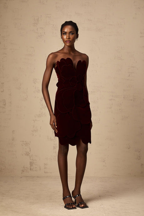 A short red velvet mini dress with floral appliques adorning the fabric