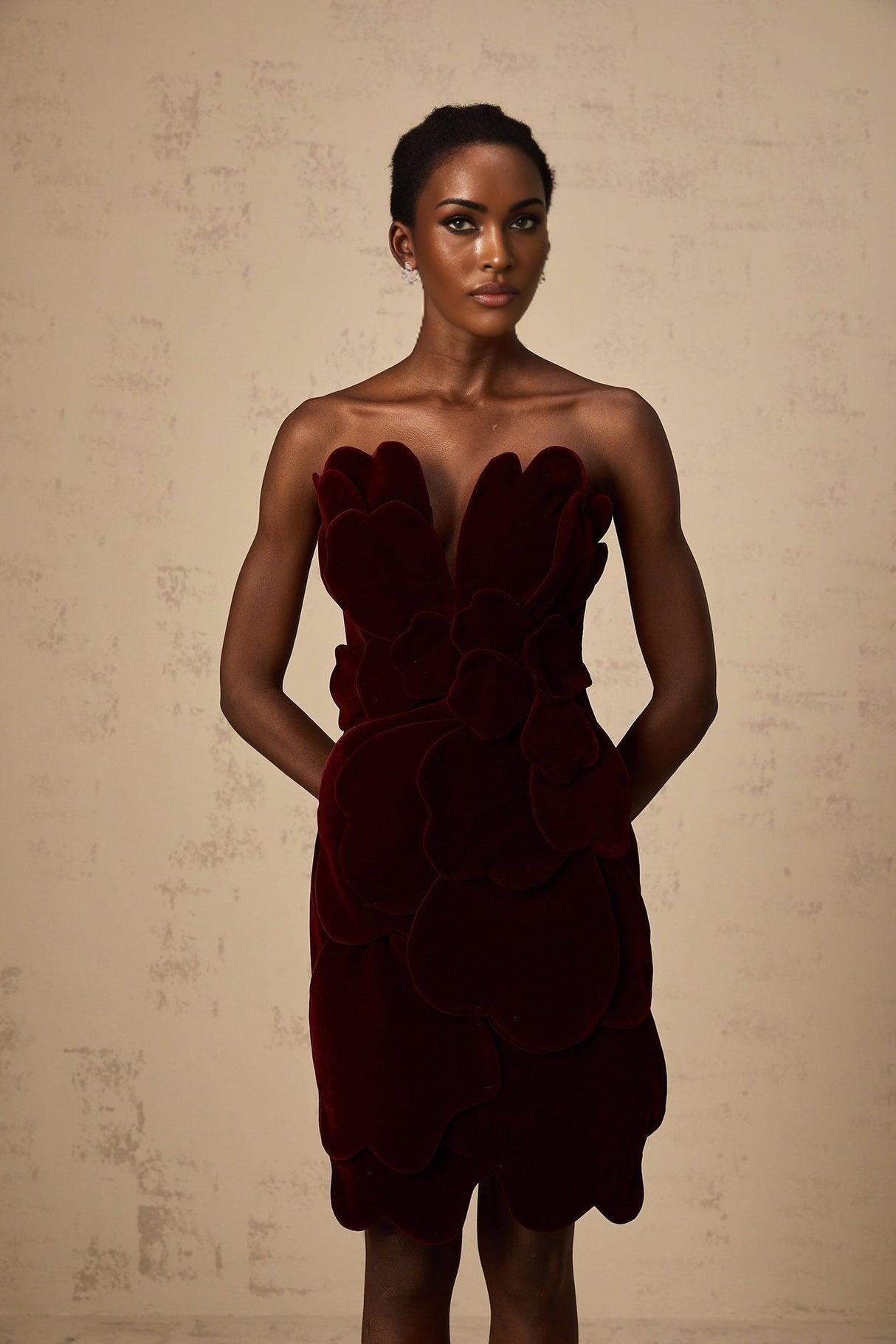 A short red velvet mini dress with floral appliques adorning the fabric